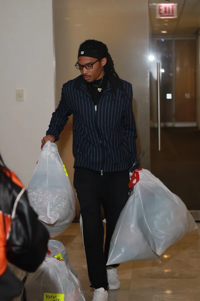 Osiris carrying bags of donated clothes for community drives.
